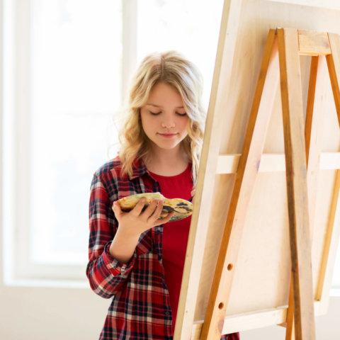 student girl with easel painting at art school PVPQ9UA scaled